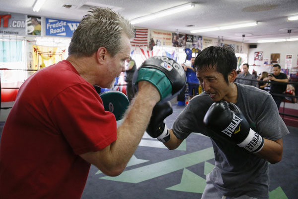 Two-time Olympic gold medalist and three-time world amateur boxing champion Zou Shiming of China works out with trainer Freddie Roach (L) at Wild Card Boxing Club for his upcoming professional boxing debut, in Los Angeles, March 20, 2013.