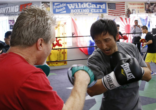 Two-time Olympic gold medalist and three-time world amateur boxing champion Zou Shiming of China works out with trainer Freddie Roach (L) at Wild Card Boxing Club for his upcoming professional boxing debut, in Los Angeles, March 20, 2013. 