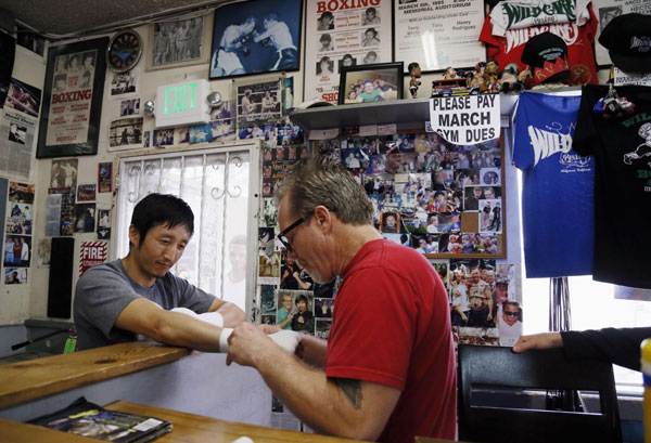 Two-time Olympic gold medalist and three-time world amateur boxing champion Zou Shiming of China (L) has his hands wrapped by trainer Freddie Roach at Wild Card Boxing Club as he trains for his upcoming professional boxing debut, in Los Angeles, March 20, 2013.