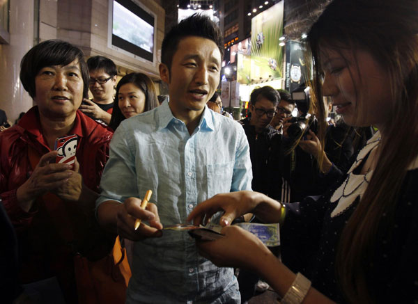 Chinese boxer Zou Shiming is surrounded by mainland Chinese visitors as he signs an autograph during a promotional event in Hong Kong, March 27, 2013.