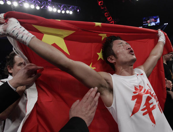 China's Zou Shiming, two-time Olympic gold medal winner and three-time World Amateur Champion, celebrates his win with a Chinese national flag after beating Mexico's Eleazar Valenzuela during his professional debut at Cotai Arena inside Venetian Macao in Macao, early April 7, 2013.