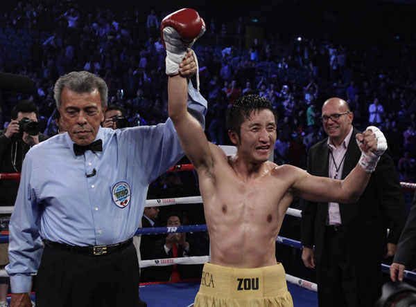 China's Zou Shiming (R), two-time Olympic gold medal winner and three-time World Amateur Champion, celebrates his win over Mexico's Eleazar Valenzuela during his professional debut at Cotai Arena inside Venetian Macao in Macao, early April 7, 2013.