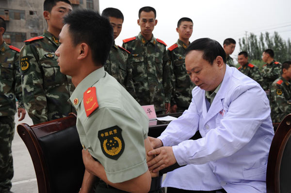 Zhuang Shihua examines a soldier in Urumqi, Xinjiang Uygur autonomous region, May 28, 2012. [Photo/Xinhua]