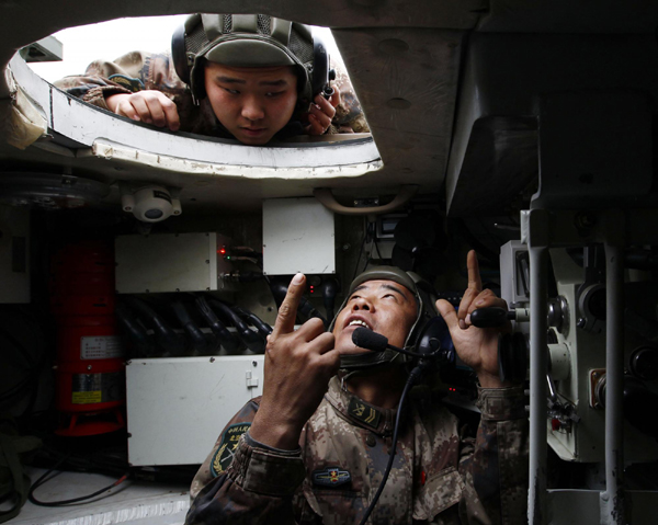 Jia Yuanyou, a delegate of the 18th CPC National Congress and artilleryman, points up to the mechanics for another soldier in Beijing, Nov 24, 2011.[Photo/Xinhua]
