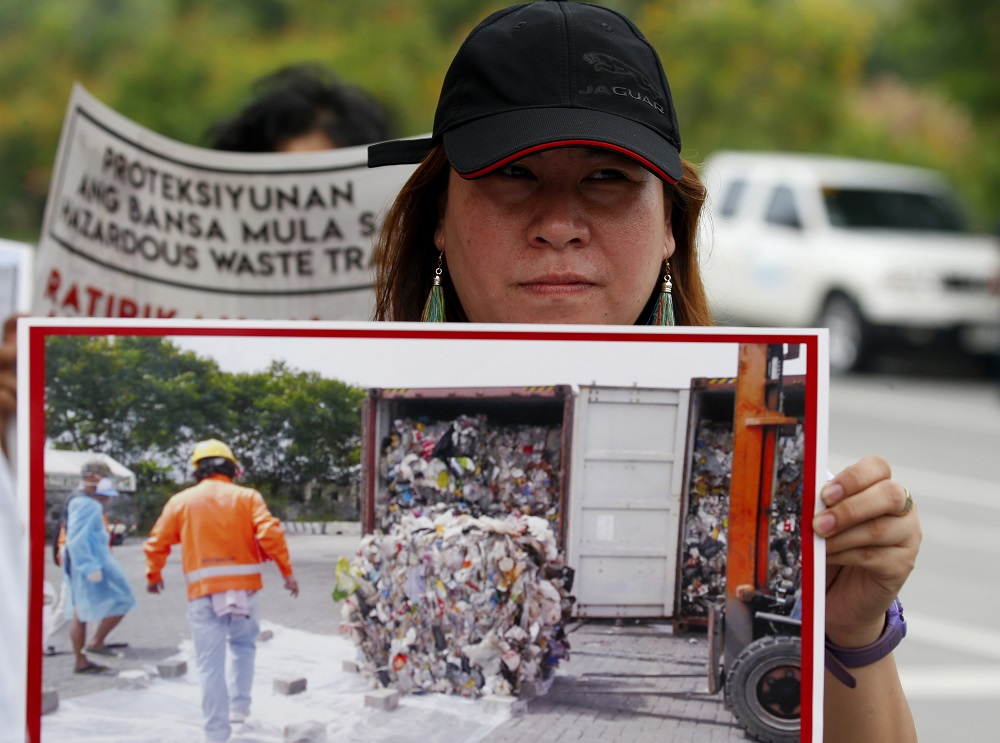 An environmentalist displays a photo of a container of garbage from Canada at a protest in May at the Philippine Senate to demand the Canadian government remove the garbage shipped to the country six years ago in suburban Pasay city, south of Manila. Image: BULLIT MARQUEZ/ASSOCIATED PRESS