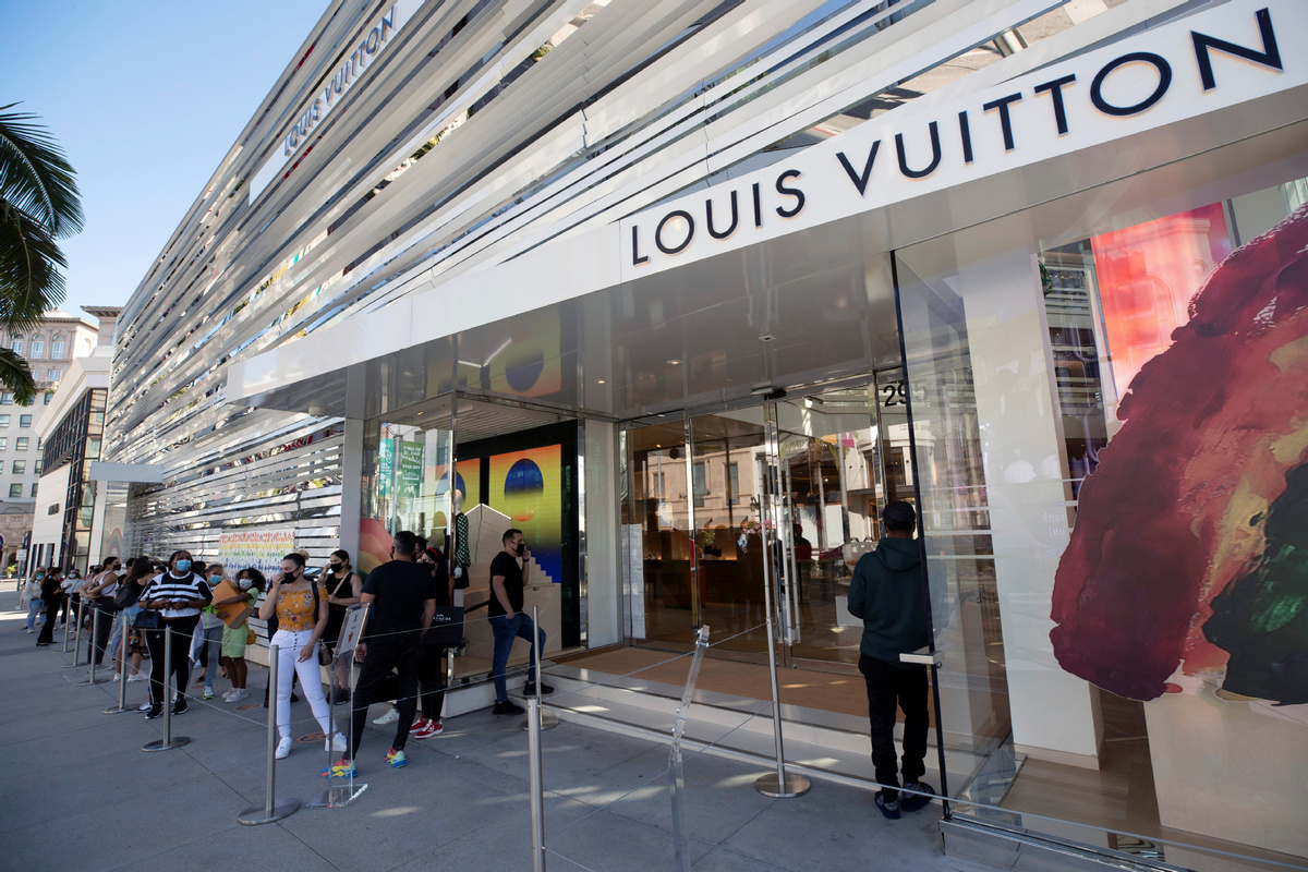 Shoppers in masks wait in line at the Louis Vuitton store in the