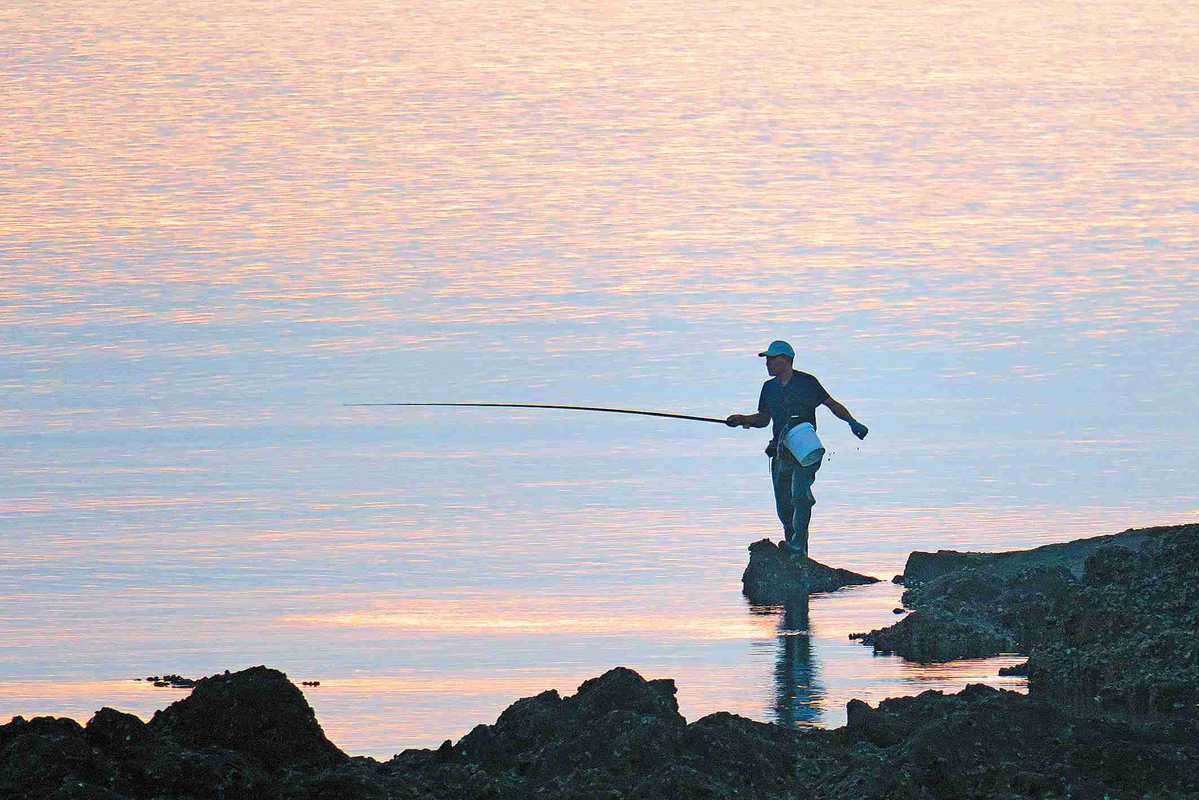 Man Fishing In Lake Relaxing In Folding Chair High-Res Stock Photo